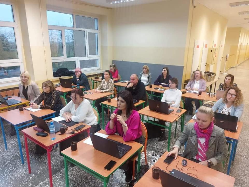 Nauczyciele siedzący przy komputerach na korytarzu szkolnym 
