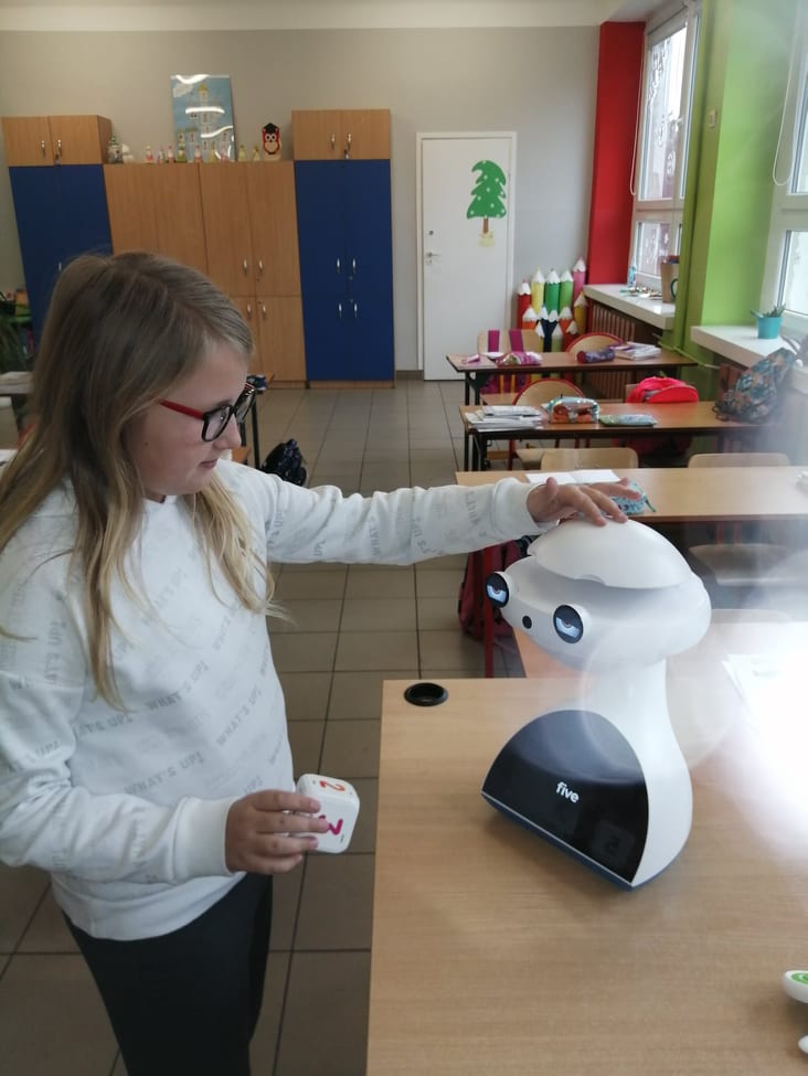 Dziewczynka głaszcze po głowie robota