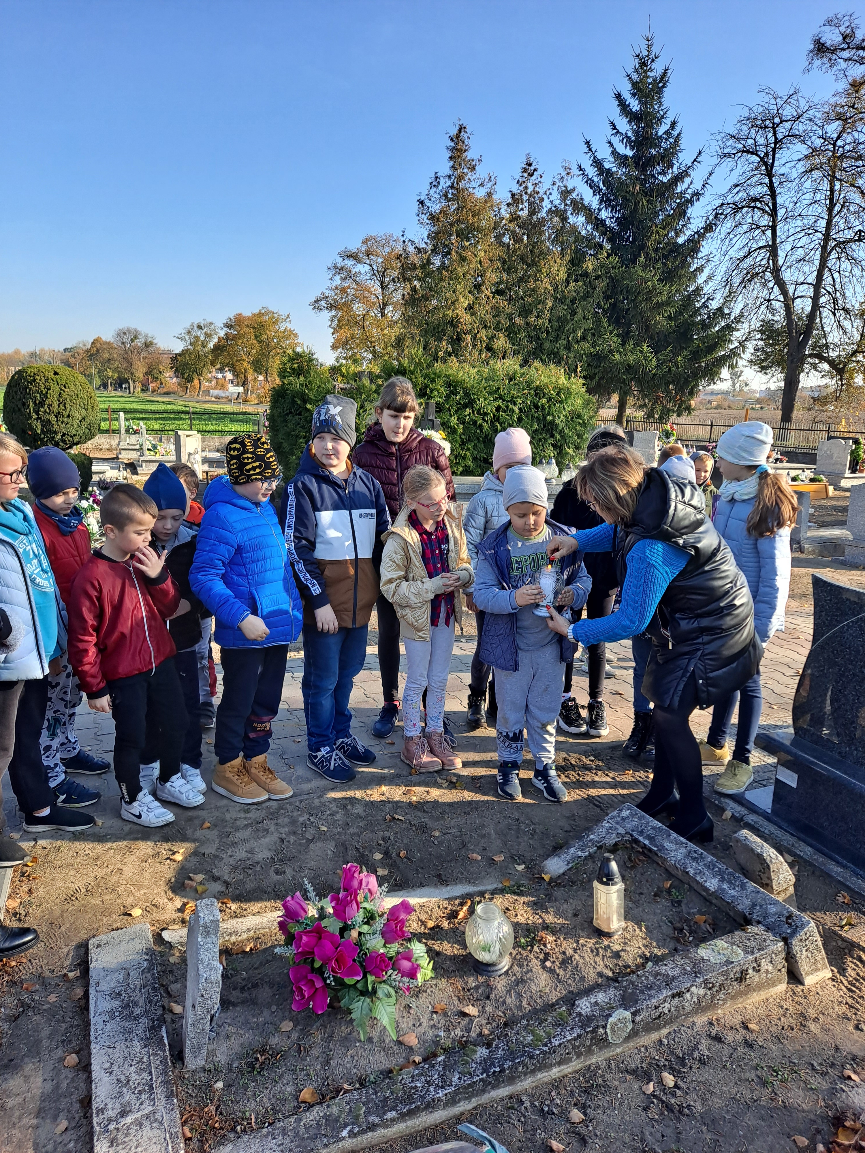 uczniowie porządkujący groby na cmentarzu