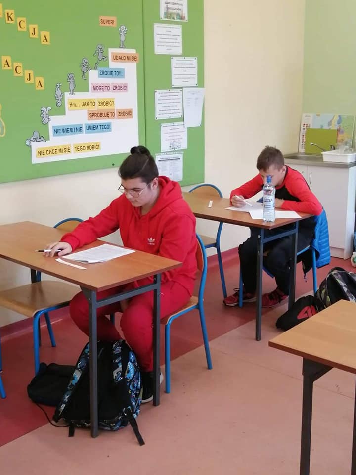 Uczniowie siedzący w ławce i rozwiązujący test
