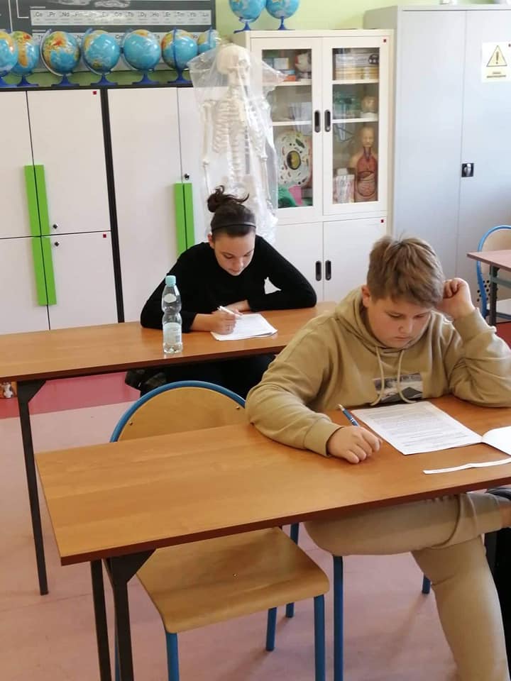 Uczeń siedzący w ławce i rozwiązujący test