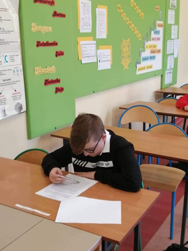 Uczeń siedzący w ławce i rozwiązujący test